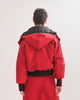 Back view of a person wearing a red  bomber jacket with detachable hood with black accents on the elasticated waist and cuffs on a white background