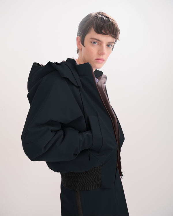 Person wearing a black, waterproof, bomber jacket on a white background