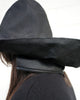 Close-up of a person wearing a black rain hat, showing the zipper that attaches to the coat