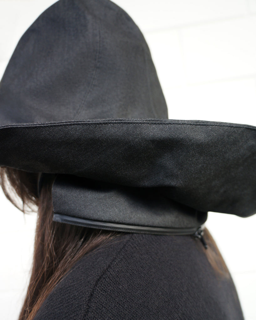 Close-up of a person wearing a black rain hat, showing the zipper that attaches to the coat
