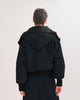  Back view of a person wearing a black, waterproof, bomber jacket on a white background
