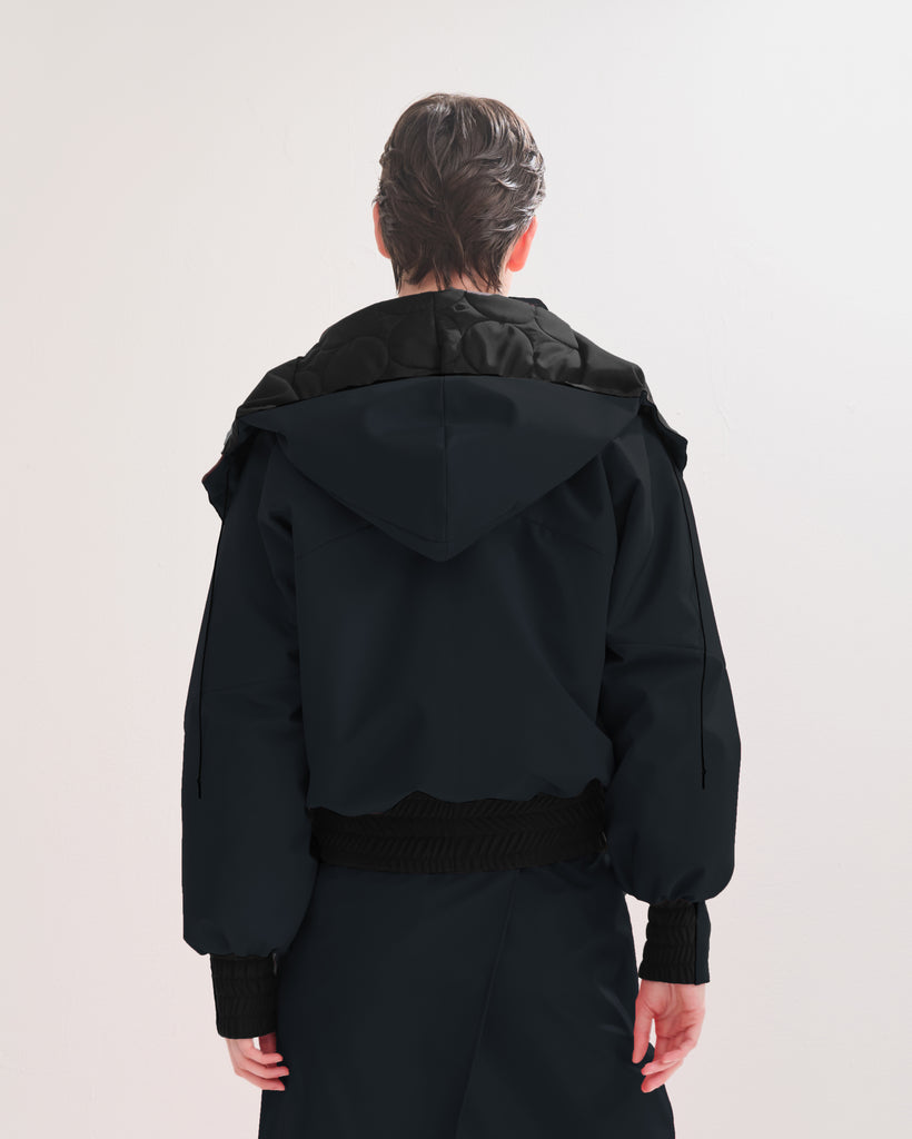  Back view of a person wearing a black, waterproof, bomber jacket on a white background