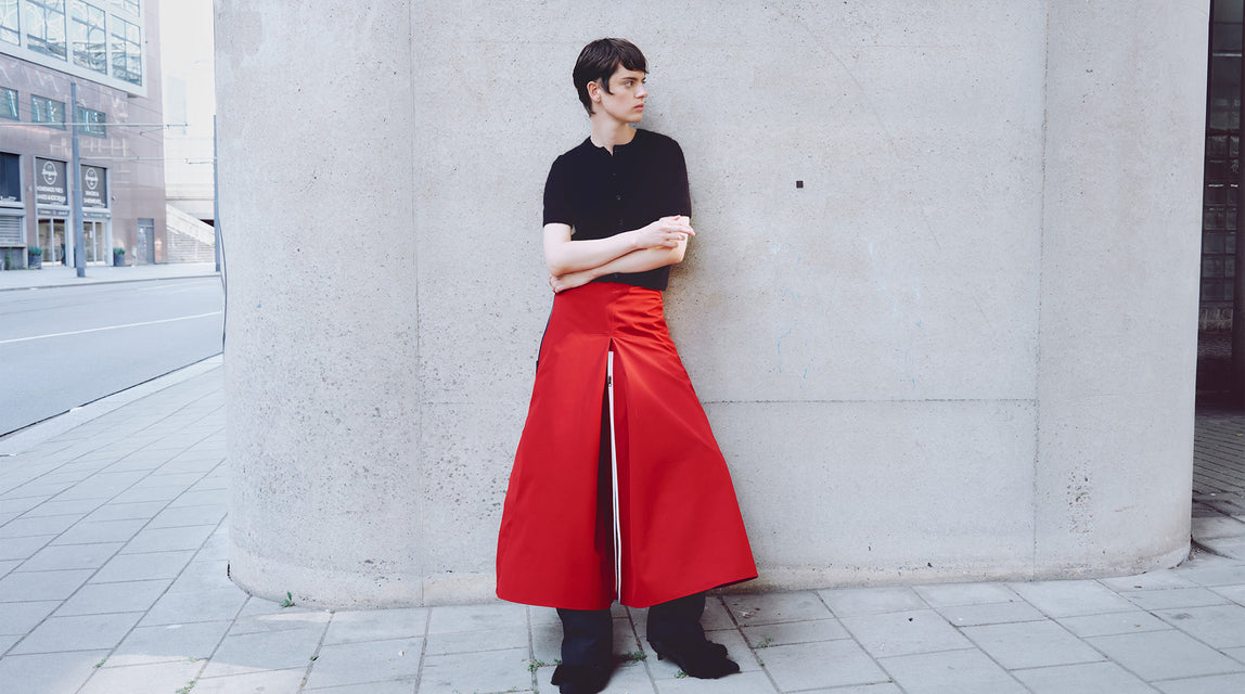 person wearing red, unisex moxie rainskirt that transforms into trousers