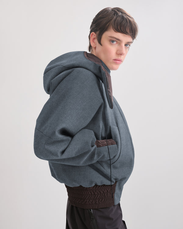 side view of person wearing a denim waterproof bomber with brown accents on a plain background