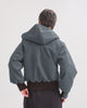 Person wearing a denim hooded jacket on a plain background