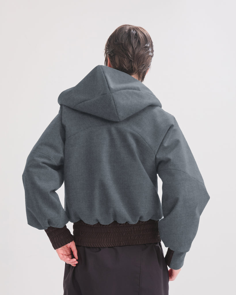 Person wearing a denim hooded jacket on a plain background