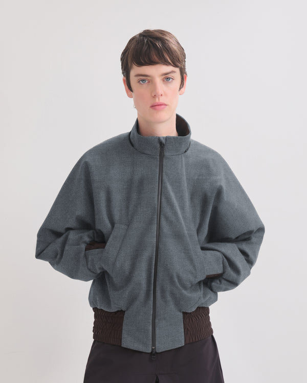 Person wearing a denim bomber jacket with a white background