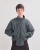 Person wearing a denim bomber jacket with a white background