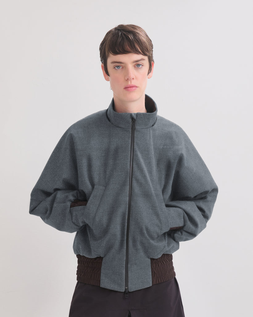 Person wearing a denim bomber jacket with a white background