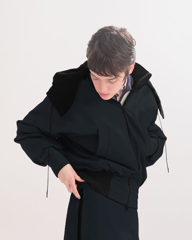 Person wearing a black, waterproof, bomber jacket with elasticated waist and cuffs, on a white background