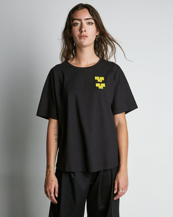 Black, short sleeved t-shirt made of hemp with a yelloe, embroidery logo on the left side of chest. Front view