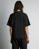 Black, short sleeved t-shirt made of hemp with a yelloe, embroidery logo on the left side of chest. Back view