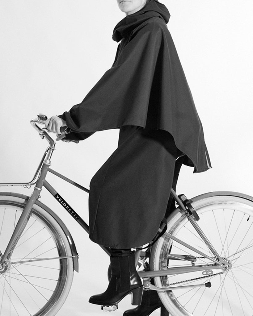 woman riding a bicycle wearing the BY BROWN raindress that is waterproof, breathable  and gives full movement on the bike
