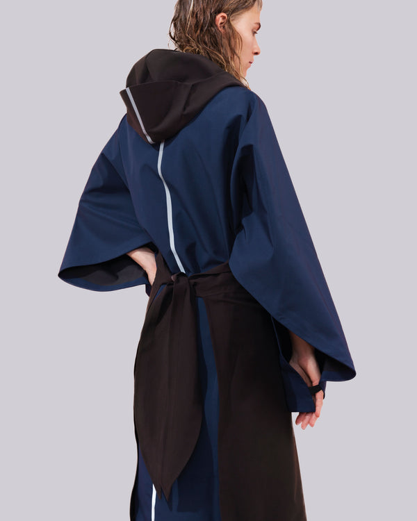 this open cape is a combination of black and blue with a hood and a reflective stripe down the back.