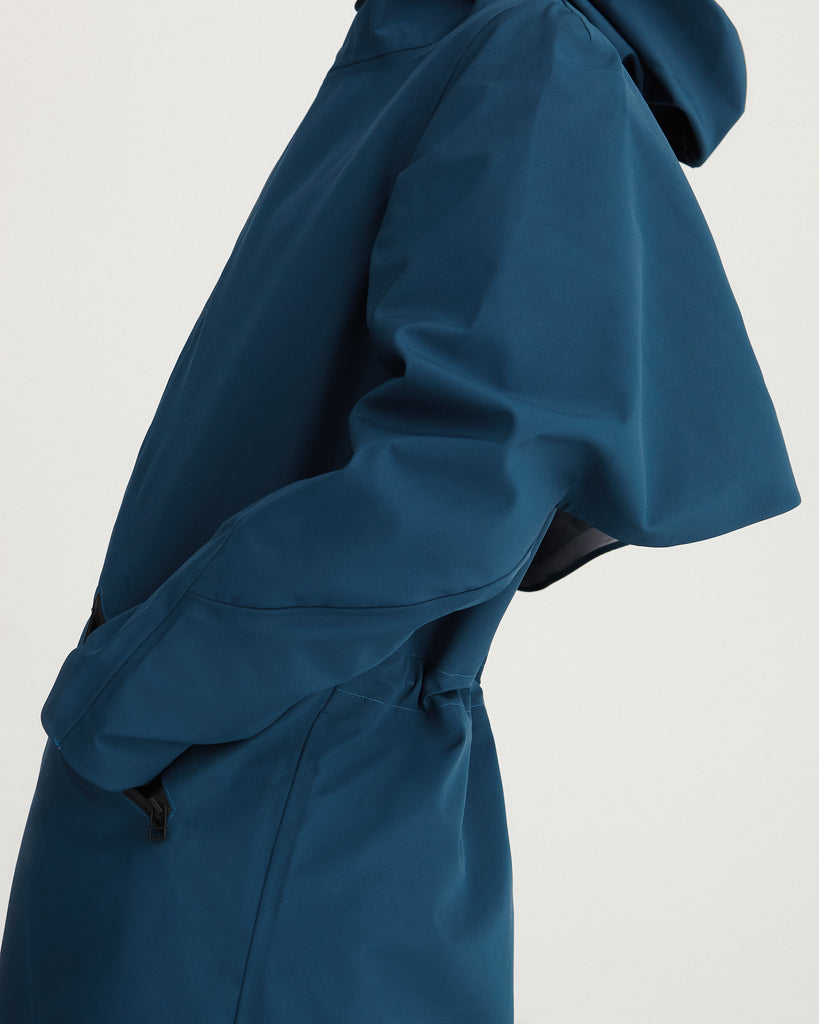 Close up of the long, blue, waterproof, breathable, technical and sustainable winter warm raincoat with recycled, detachable liner.