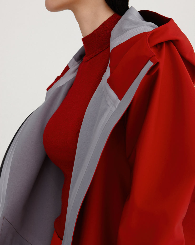 close up of sealed seams from midlength, red, waterproof, breathable, sustainable and technical raincoat from recycled materials with hood.